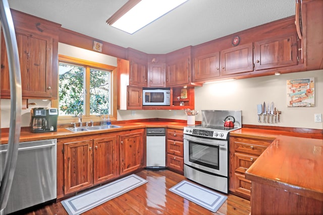 kitchen with stainless steel appliances, light hardwood / wood-style flooring, and sink