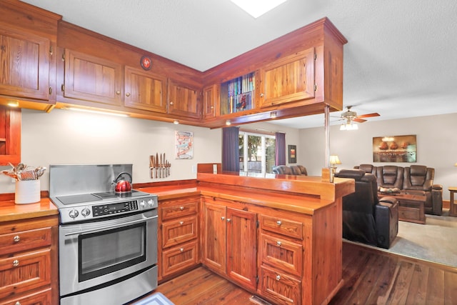 kitchen featuring ceiling fan, kitchen peninsula, dark hardwood / wood-style floors, and electric stove