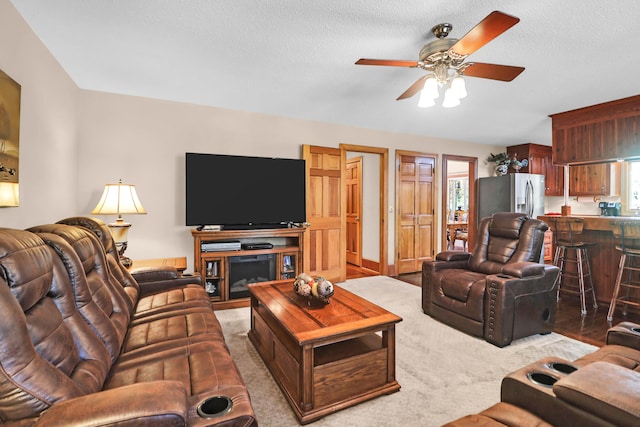 living room featuring ceiling fan, carpet, and a textured ceiling