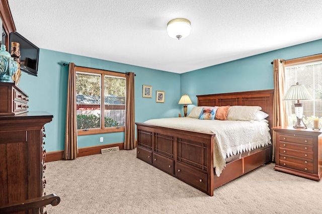 bedroom with a textured ceiling and light carpet