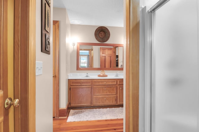 bathroom featuring vanity, a textured ceiling, hardwood / wood-style flooring, and an enclosed shower