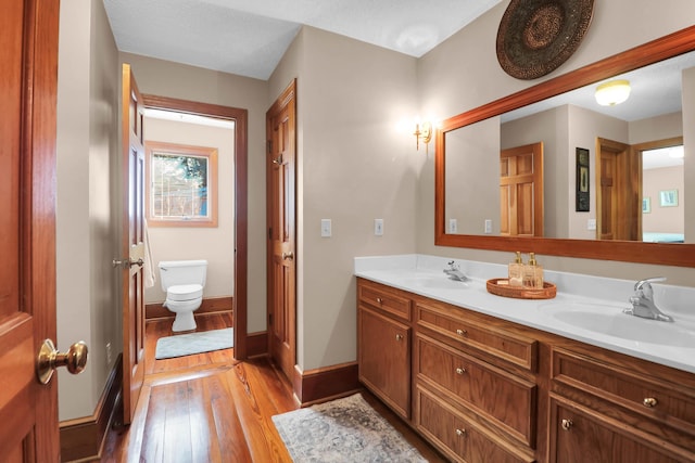 bathroom featuring toilet, wood-type flooring, and vanity