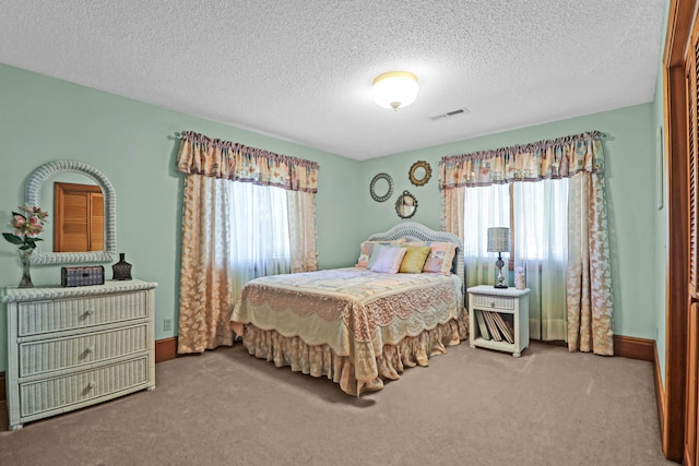 bedroom with light carpet, a textured ceiling, and multiple windows