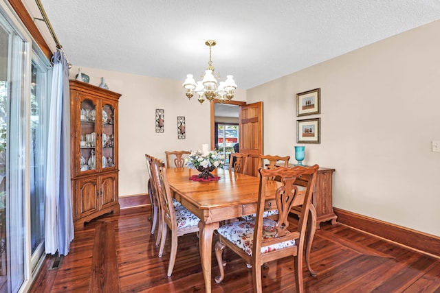 dining space with dark hardwood / wood-style flooring, an inviting chandelier, and a textured ceiling