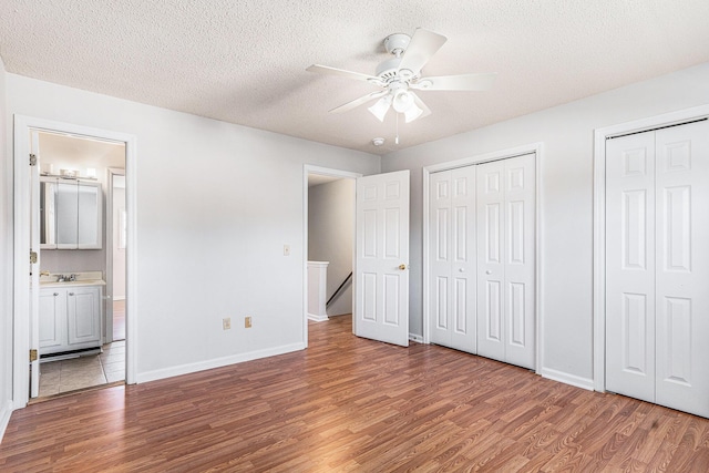 111 Elmwood Ave Unit A, Ladson, SC 29456 - unfurnished bedroom featuring wood finished floors, two closets, a textured ceiling, baseboards, and ensuite bath