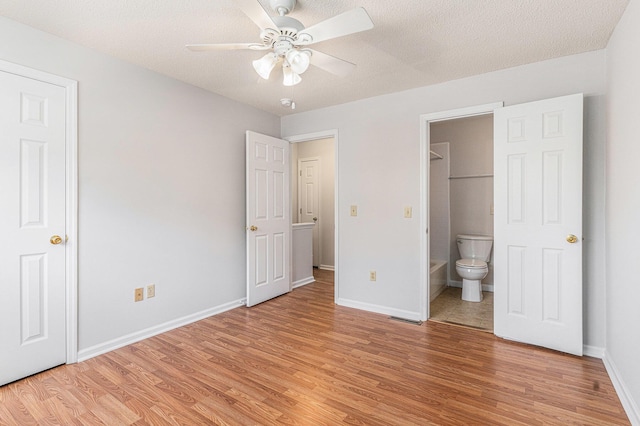 111 Elmwood Ave Unit A, Ladson, SC 29456 - unfurnished bedroom with light wood-style flooring, baseboards, ensuite bathroom, a textured ceiling, and ceiling fan