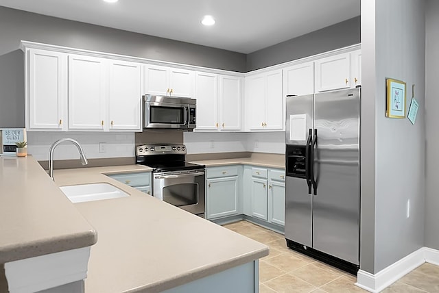 kitchen featuring sink, stainless steel appliances, light tile patterned floors, kitchen peninsula, and white cabinets