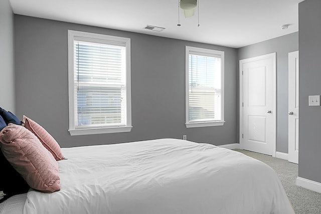 bedroom featuring multiple windows, ceiling fan, and light colored carpet