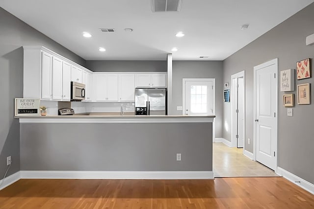 kitchen featuring kitchen peninsula, light wood-type flooring, white cabinetry, and stainless steel appliances