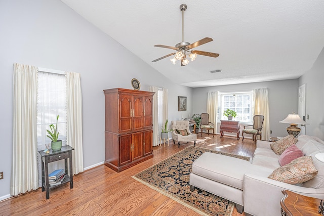 living room with a textured ceiling, ceiling fan, light hardwood / wood-style flooring, and high vaulted ceiling