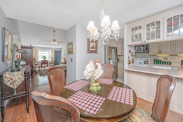 dining space with a textured ceiling, light hardwood / wood-style floors, and ceiling fan with notable chandelier