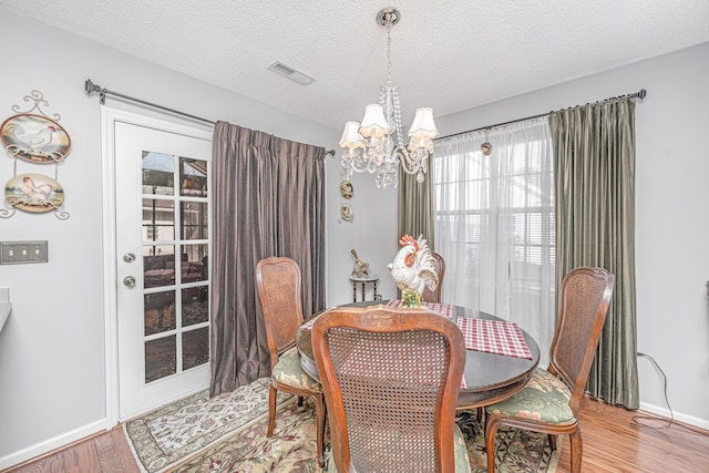 dining room with a textured ceiling, a chandelier, and hardwood / wood-style floors