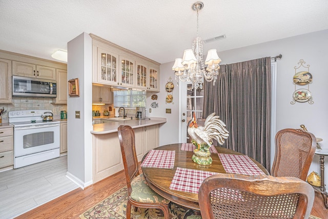 dining area featuring light hardwood / wood-style floors, sink, a textured ceiling, and a chandelier