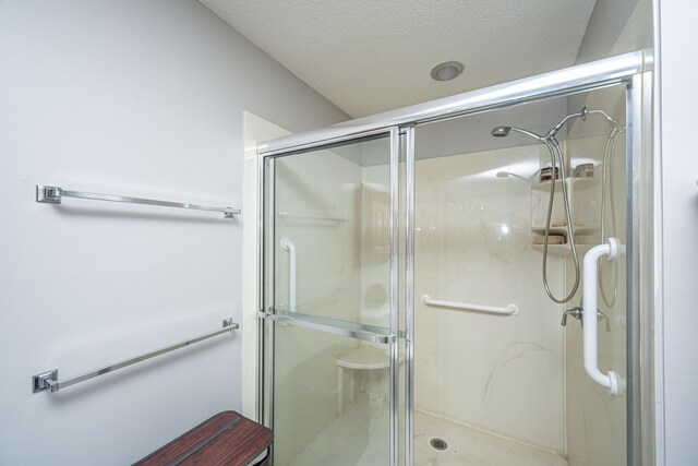 bathroom featuring a shower with shower door and a textured ceiling