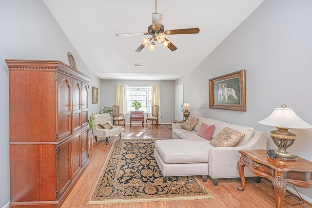 living room featuring ceiling fan, light wood-type flooring, and lofted ceiling