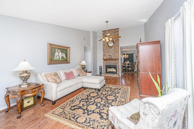 living room featuring vaulted ceiling, a brick fireplace, hardwood / wood-style floors, and ceiling fan