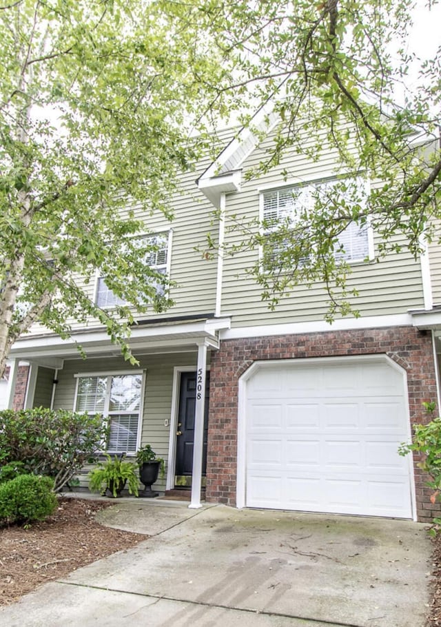 multi unit property featuring an attached garage, concrete driveway, and brick siding