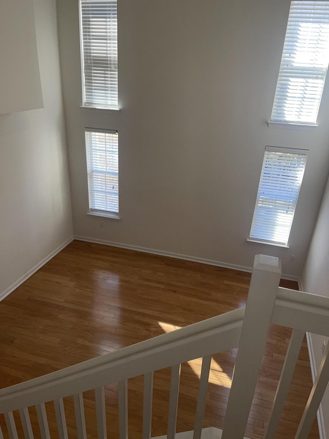 unfurnished room with a wealth of natural light, a high ceiling, baseboards, and wood finished floors