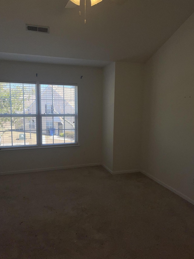 empty room with carpet, visible vents, and baseboards