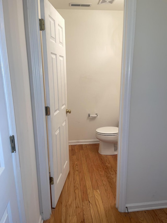 bathroom with toilet, baseboards, visible vents, and wood finished floors