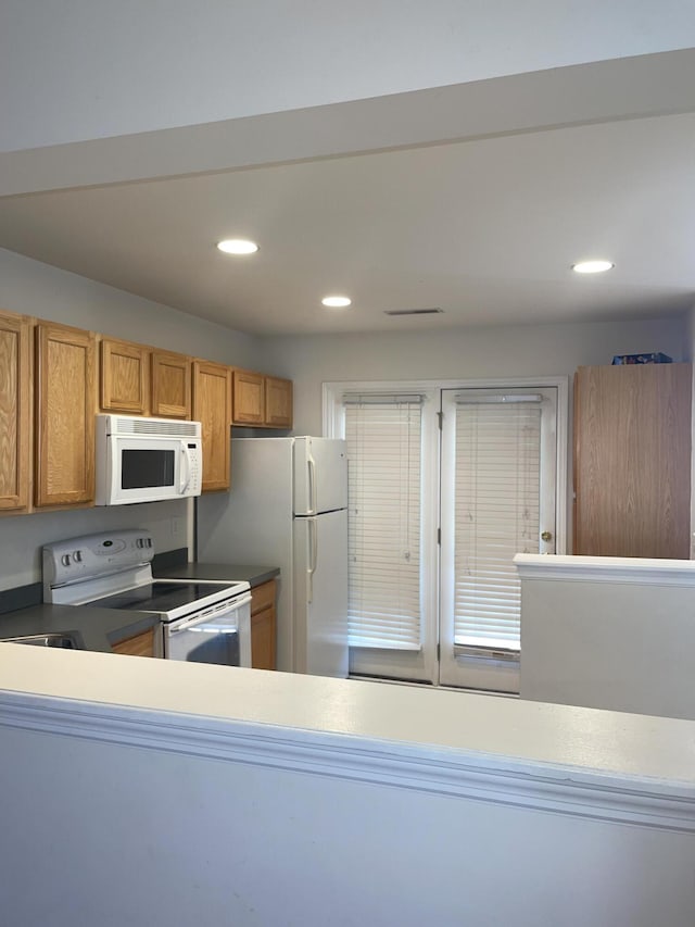 kitchen featuring recessed lighting, white appliances, brown cabinets, and visible vents