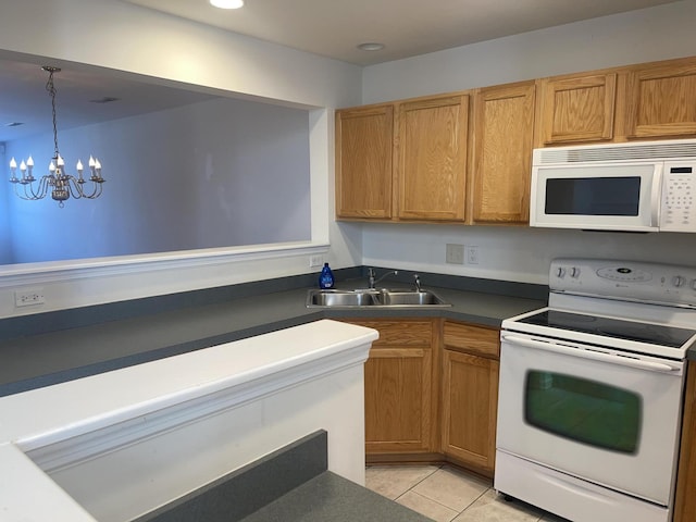 kitchen featuring white appliances, dark countertops, a sink, a notable chandelier, and light tile patterned flooring