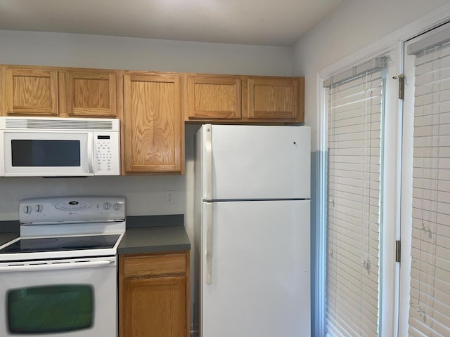 kitchen featuring dark countertops, white appliances, and brown cabinets