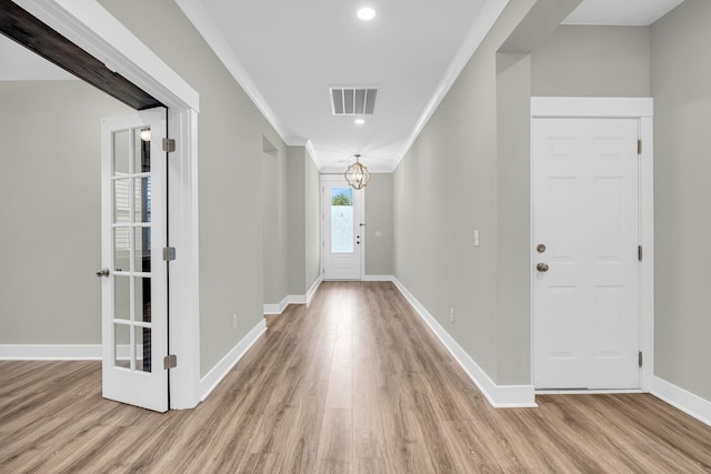 hall featuring a notable chandelier, light hardwood / wood-style floors, and crown molding