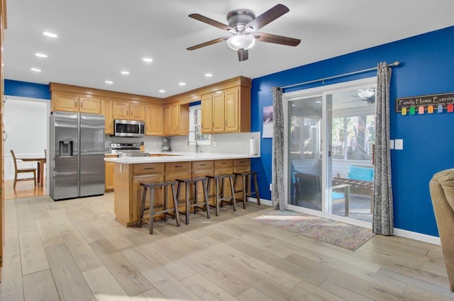 kitchen with decorative backsplash, light hardwood / wood-style floors, kitchen peninsula, and stainless steel appliances