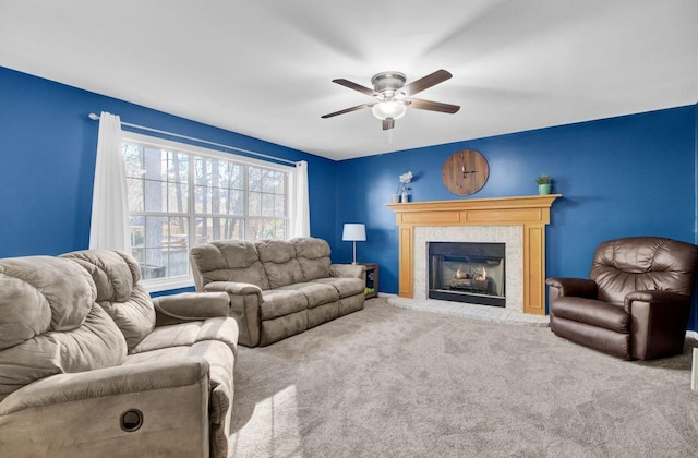 carpeted living room featuring ceiling fan and a tiled fireplace