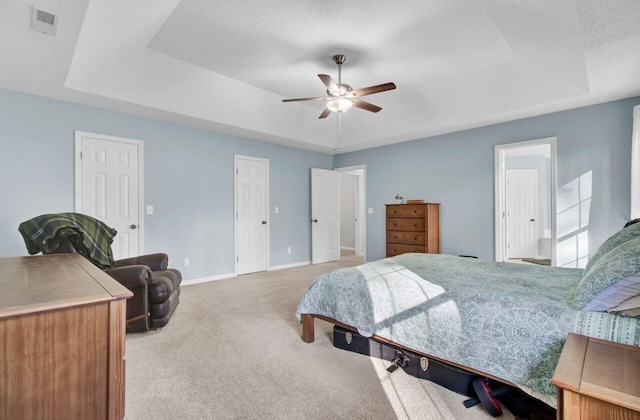 carpeted bedroom with ceiling fan, a textured ceiling, and a raised ceiling