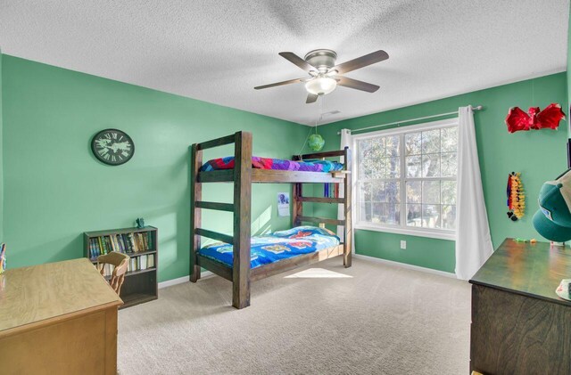 carpeted bedroom featuring ceiling fan and a textured ceiling