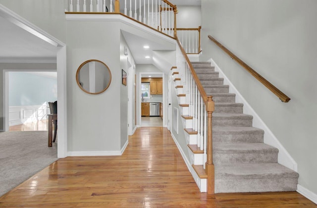 stairs with ornamental molding and hardwood / wood-style floors