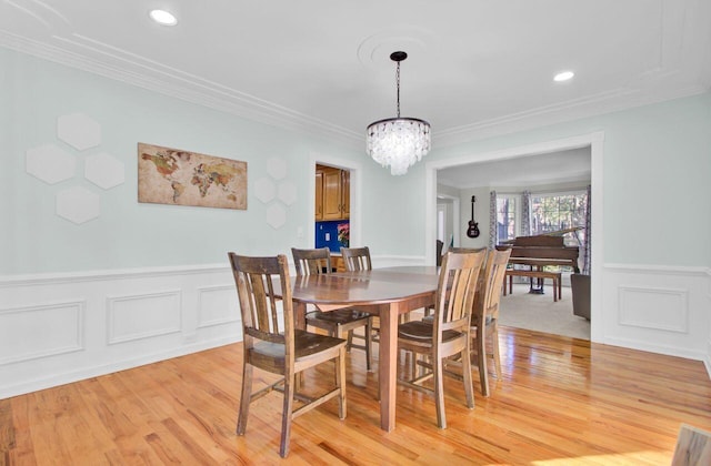 dining space with crown molding, light hardwood / wood-style floors, and a notable chandelier