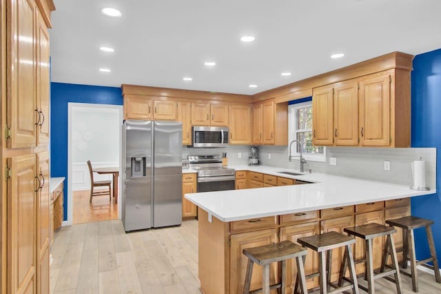 kitchen with a kitchen bar, tasteful backsplash, sink, kitchen peninsula, and stainless steel appliances