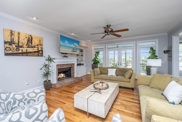 living room featuring ornamental molding, a fireplace, light wood-type flooring, and built in shelves