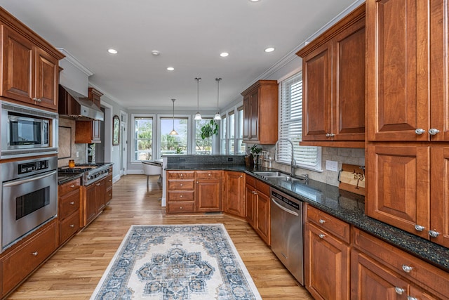 kitchen with pendant lighting, ornamental molding, appliances with stainless steel finishes, and sink