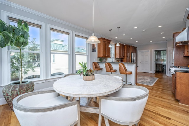 dining space featuring ornamental molding and light hardwood / wood-style floors