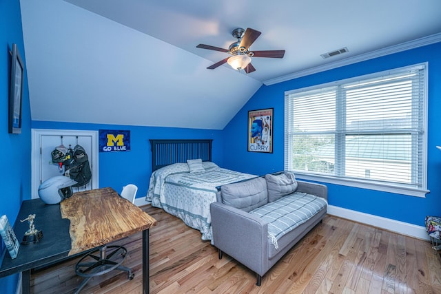 bedroom with ceiling fan, lofted ceiling, ornamental molding, and light wood-type flooring