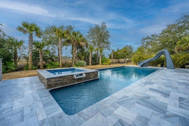 view of swimming pool with an in ground hot tub, a water slide, and a patio area