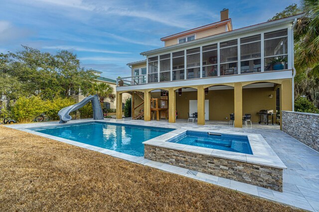 rear view of property featuring a patio, a yard, a pool with hot tub, and a sunroom