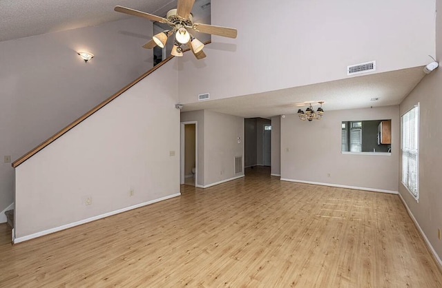 unfurnished living room featuring a textured ceiling, ceiling fan with notable chandelier, light hardwood / wood-style flooring, and high vaulted ceiling