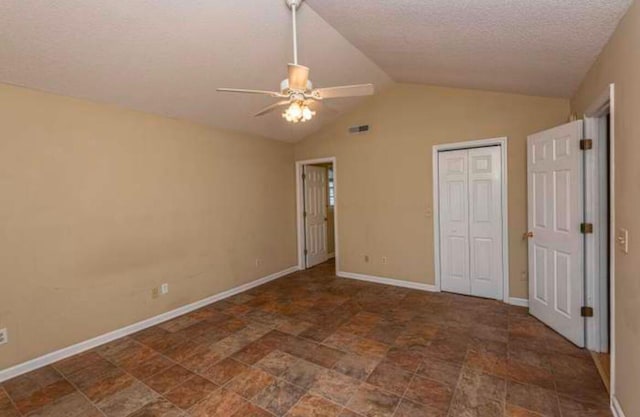 unfurnished bedroom featuring ceiling fan, a closet, a textured ceiling, and vaulted ceiling