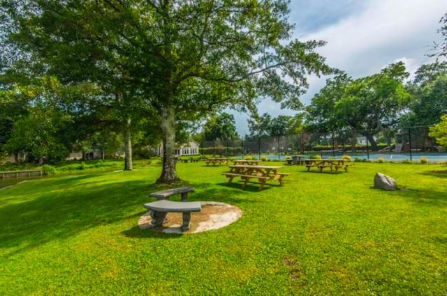 view of community featuring a lawn and tennis court