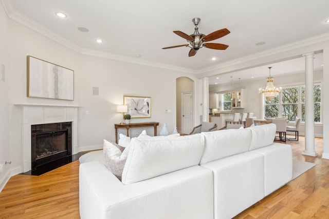 living room featuring light wood-type flooring, crown molding, and ceiling fan with notable chandelier