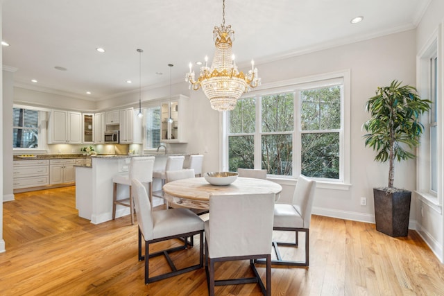 dining room featuring light wood-type flooring, a healthy amount of sunlight, and crown molding