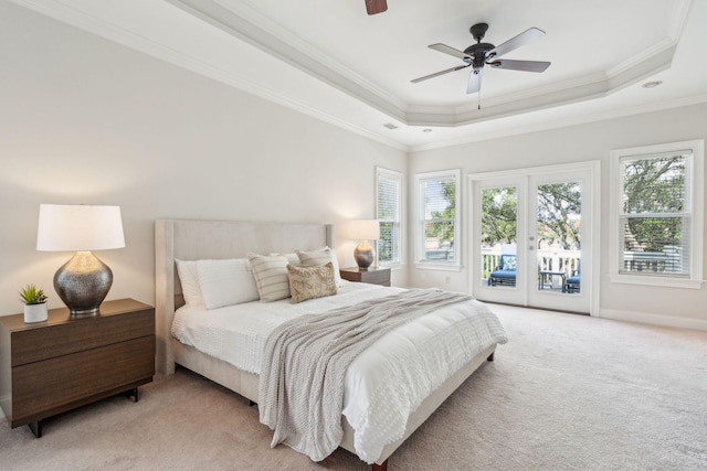 carpeted bedroom featuring ceiling fan, ornamental molding, a tray ceiling, and access to outside