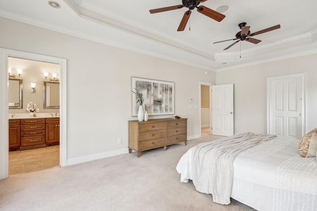 bedroom featuring ornamental molding, ensuite bath, a tray ceiling, light colored carpet, and ceiling fan