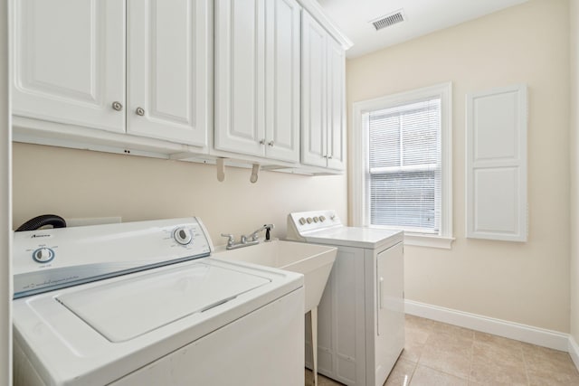 clothes washing area featuring light tile patterned flooring, cabinets, and separate washer and dryer