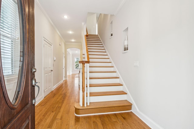 entrance foyer with ornamental molding and light hardwood / wood-style floors